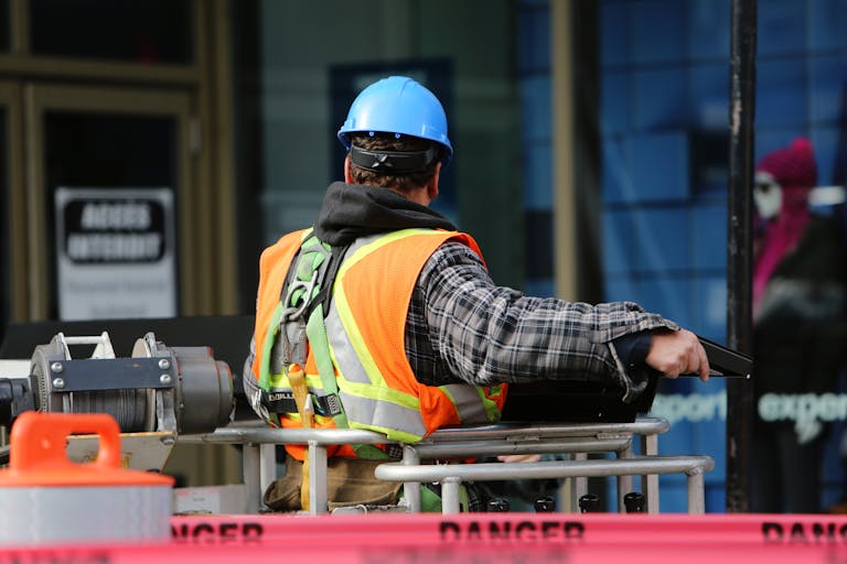 Ein Bauarbeiter, der einen blauen Helm und eine Sicherheitsweste trägt, bedient auf einer städtischen Baustelle Geräte.