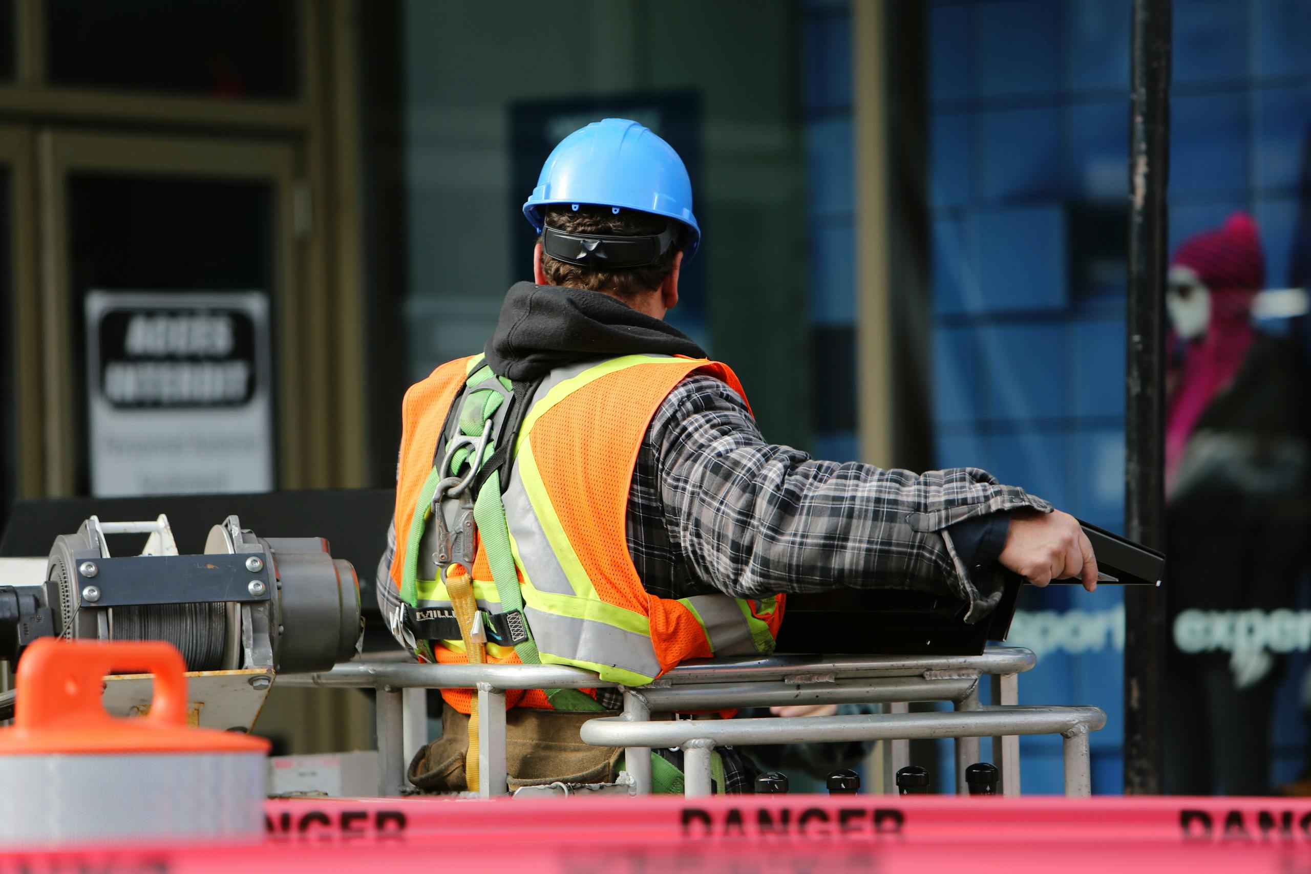 Ein Bauarbeiter, der einen blauen Helm und eine Sicherheitsweste trägt, bedient auf einer städtischen Baustelle Geräte.